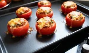 Tomates farcies au fromage gratiné sur une plaque de cuisson. Le temps de cuisson est presque terminé, le fromage est doré.