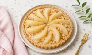 Tarte amandine aux poires, joliment décorée de lamelles d'amandes grillées et de poires tendres disposées en rosace.