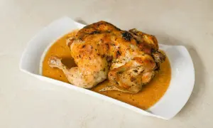 Un délicieux poulet entier, d'environ 1,5 kg, est prêt pour la cuisson au four, sa peau dorée promet un plat savoureux.