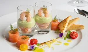 Une élégante entrée froide : crevettes et avocat en verrine, saumon roulé, toasts grillés et garnitures fraîches.