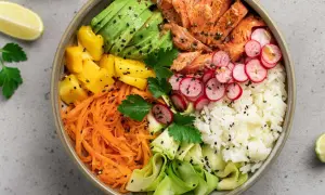 Un bol coloré avec saumon, avocat, mangue, carottes râpées, radis, courgette et riz blanc. Parfait pour des menus semaine famille équilibrés et savoureux.
