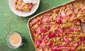 Un délicieux crumble pomme Laurent Mariotte, garni de fruits rouges et d'une touche de crème, prêt à être dégusté avec un café.