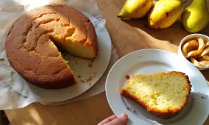 Un délicieux gâteau à la banane, encore tiède, avec des poires et des chips de pomme sur une table en bois.
