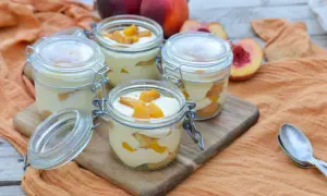 Quatre verrines de tiramisu pêche, garnies de morceaux de fruits frais. Un délice estival.