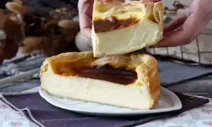 Un flan pâtissier crémeux, doré et généreux, est coupé en deux. Ses bords croustillants et sa garniture onctueuse invitent à la dégustation.