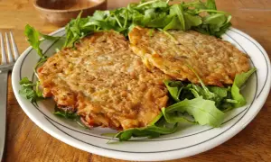 Deux galettes dorées sur un lit de roquette. Une belle assiette pour apprendre comment apprendre cuisiner.