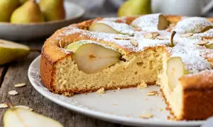 Un gâteau aux poires moelleux, saupoudré de sucre glace et décoré d'amandes effilées. Des poires fraîches sont intégrées dans la pâte.