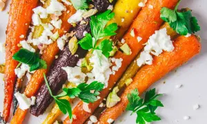 Carottes multicolores rôties, parsemées de feta émiettée, de pistaches concassées et de persil frais. Un délice pour la cuisson carottes.