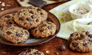 Gourmands cookies flocons d'avoine, parsemés de pépites de chocolat noir et de graines, sur une assiette rustique.