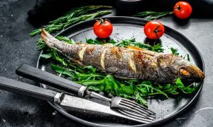 Bar entier rôti sur un lit de roquette, garni de tomates cerises. Le temps de cuisson bar au four est parfait pour ce plat savoureux.