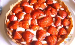 Une délicieuse tarte aux fraises, garnie de fruits rouges frais et d'une crème onctueuse, prête à être dégustée.
