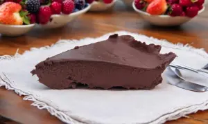 Tranche de gâteau au chocolat onctueux, servi avec des fruits rouges frais en arrière-plan. Un délice inattendu, ce gâteau courgette surprend par sa texture.