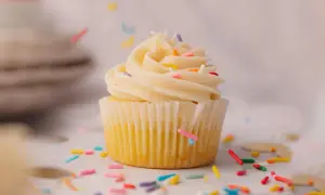 Un cupcake vanille avec glaçage crémeux et vermicelles colorés tombant. Une recette facile pour un goûter gourmand.