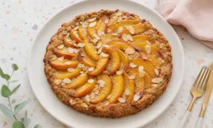 Tarte tatin aux pêches, garnie d'amandes effilées. Un délice doré et fruité.