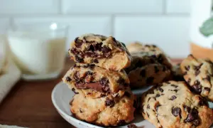 Délicieux cookies aux pépites de chocolat, parfaits pour une recette de cookies moelleux et gonflés. Un verre de lait est en arrière-plan.