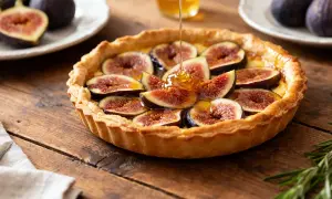 La tarte aux figues de ma grand-mère, garnie de figues fraîches et nappée de miel doré, repose sur une table en bois rustique.