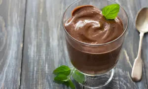 Crème au chocolat onctueuse, décorée d'une feuille de menthe, comme celle de Laurent Mariotte. Une cuillère argentée est à côté.
