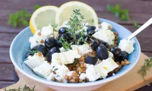 Salade de lentilles, feta, olives noires et citron, garnie de thym frais. Un délice méditerranéen.