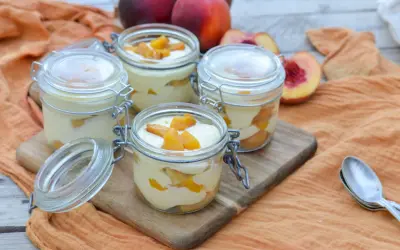 Quatre verrines de tiramisu pêche, garnies de morceaux de fruits frais. Un délice estival.