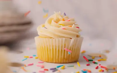 Un cupcake vanille avec glaçage crémeux et vermicelles colorés tombant. Une recette facile pour un goûter gourmand.