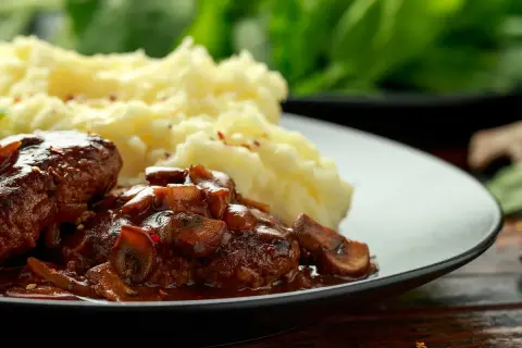 Délicieuses joue de boeuf en sauce avec des champignons, servies avec une purée de pommes de terre onctueuse.