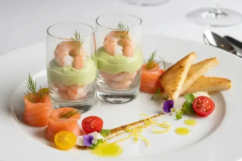 Une élégante entrée froide : crevettes et avocat en verrine, saumon roulé, toasts grillés et garnitures fraîches.