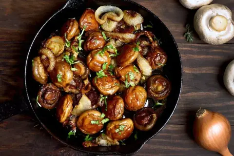 Poêlée de champignons et oignons caramélisés, une délicieuse cuisson des cèpes, garnie de persil frais.