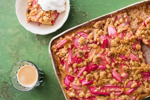 Un délicieux crumble pomme Laurent Mariotte, garni de fruits rouges et d'une touche de crème, prêt à être dégusté avec un café.