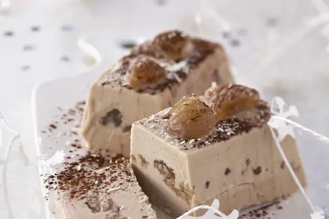 Tranches d'une délicieuse recette buche aux marrons, garnies de marrons glacés et saupoudrées de cacao.