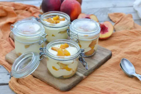 Quatre verrines de tiramisu pêche, garnies de morceaux de fruits frais. Un délice estival.