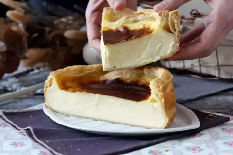 Un flan pâtissier crémeux, doré et généreux, est coupé en deux. Ses bords croustillants et sa garniture onctueuse invitent à la dégustation.