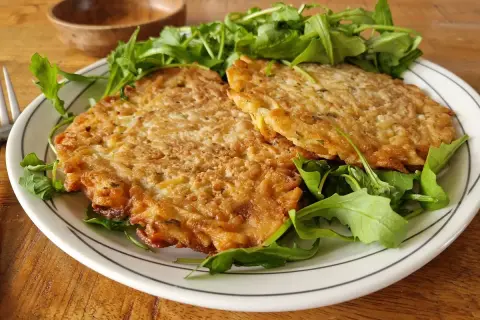 Deux galettes dorées sur un lit de roquette. Une belle assiette pour apprendre comment apprendre cuisiner.