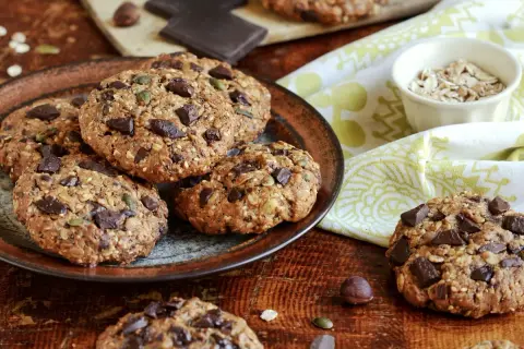 Gourmands cookies flocons d'avoine, parsemés de pépites de chocolat noir et de graines, sur une assiette rustique.