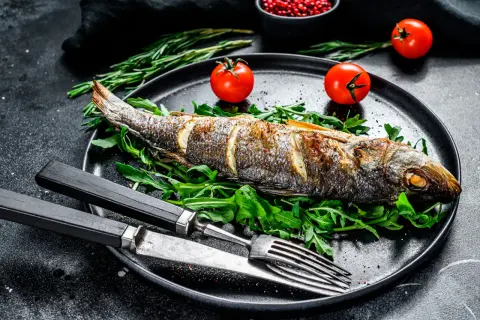 Bar entier rôti sur un lit de roquette, garni de tomates cerises. Le temps de cuisson bar au four est parfait pour ce plat savoureux.