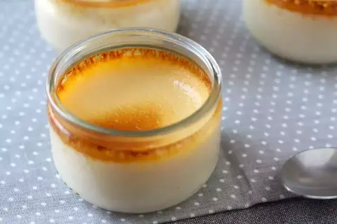 Crème aux œufs on a polka dot cloth, with a spoon nearby. The dessert has a golden, caramelized top.