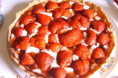Une délicieuse tarte aux fraises, garnie de fruits rouges frais et d'une crème onctueuse, prête à être dégustée.