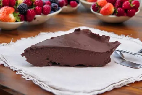 Tranche de gâteau au chocolat onctueux, servi avec des fruits rouges frais en arrière-plan. Un délice inattendu, ce gâteau courgette surprend par sa texture.