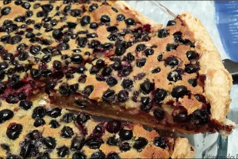 Une part généreuse de tarte aux cassis, garnie de fruits noirs juteux et d'une pâte dorée. Un délice gourmand.