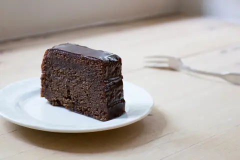 Tranche de fondant au chocolat Laurent Mariotte, nappée d'un glaçage brillant, sur une assiette blanche. Une fourchette est posée à côté.