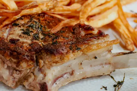 Une côte de veau au four, dorée et savoureuse, accompagnée de frites croustillantes. Un plat réconfortant pour un repas gourmand.