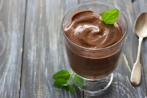 Crème au chocolat onctueuse, décorée d'une feuille de menthe, comme celle de Laurent Mariotte. Une cuillère argentée est à côté.