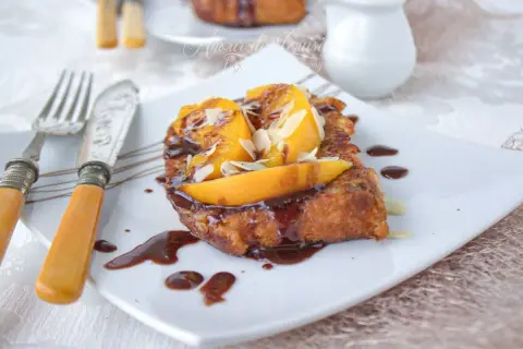 Une délicieuse brioche perdue, nappée de chocolat et garnie de fruits et d'amandes effilées, prête à être dégustée.