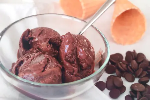 Un bol de semifreddo chocolat, avec des pépites de chocolat et des cornets à glace en arrière-plan.