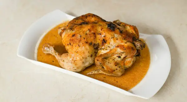 Un délicieux poulet entier, d'environ 1,5 kg, est prêt pour la cuisson au four, sa peau dorée promet un plat savoureux.