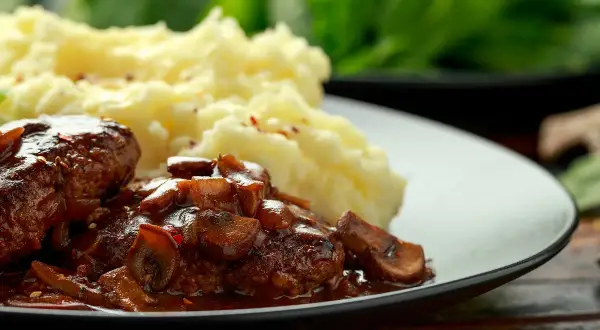 Délicieuses joue de boeuf en sauce avec des champignons, servies avec une purée de pommes de terre onctueuse.
