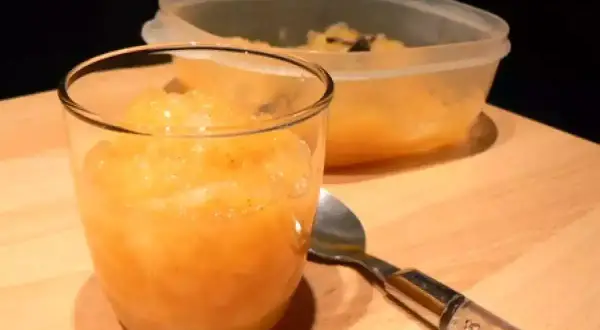 Compote pomme poire vanille dans un verre, avec une cuillère et un récipient en arrière-plan.