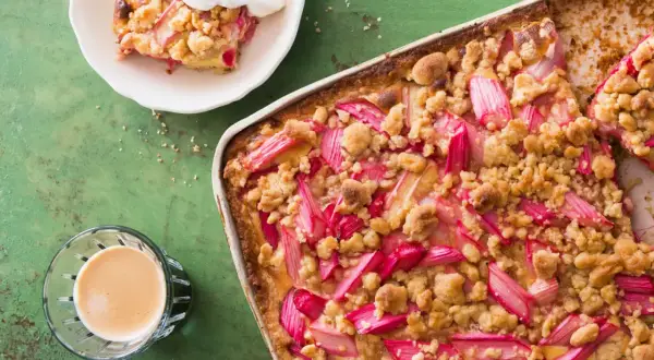Un délicieux crumble pomme Laurent Mariotte, garni de fruits rouges et d'une touche de crème, prêt à être dégusté avec un café.