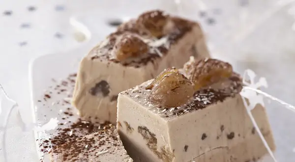 Tranches d'une délicieuse recette buche aux marrons, garnies de marrons glacés et saupoudrées de cacao.