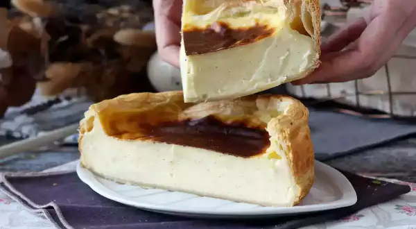 Un flan pâtissier crémeux, doré et généreux, est coupé en deux. Ses bords croustillants et sa garniture onctueuse invitent à la dégustation.