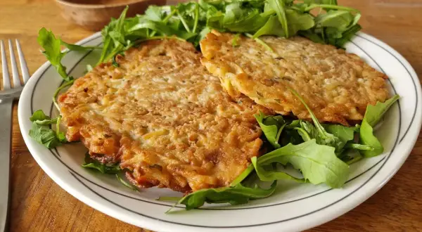Deux galettes dorées sur un lit de roquette. Une belle assiette pour apprendre comment apprendre cuisiner.